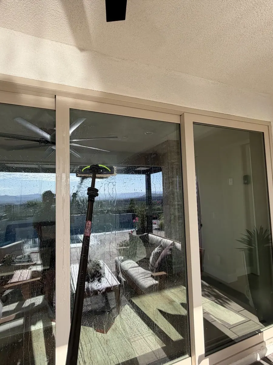 Sliding door reflecting a ceiling fan and mountain-view pool patio