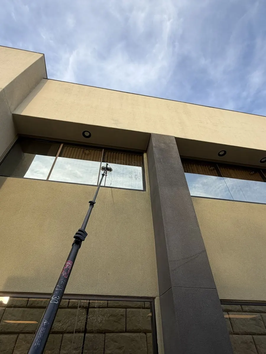 Extension-pole cleaning on a modern two-story home, dramatic upward angle